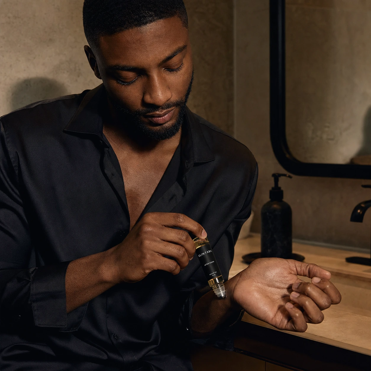 Adult Black man applying Klintara perfume oil to his wrist
