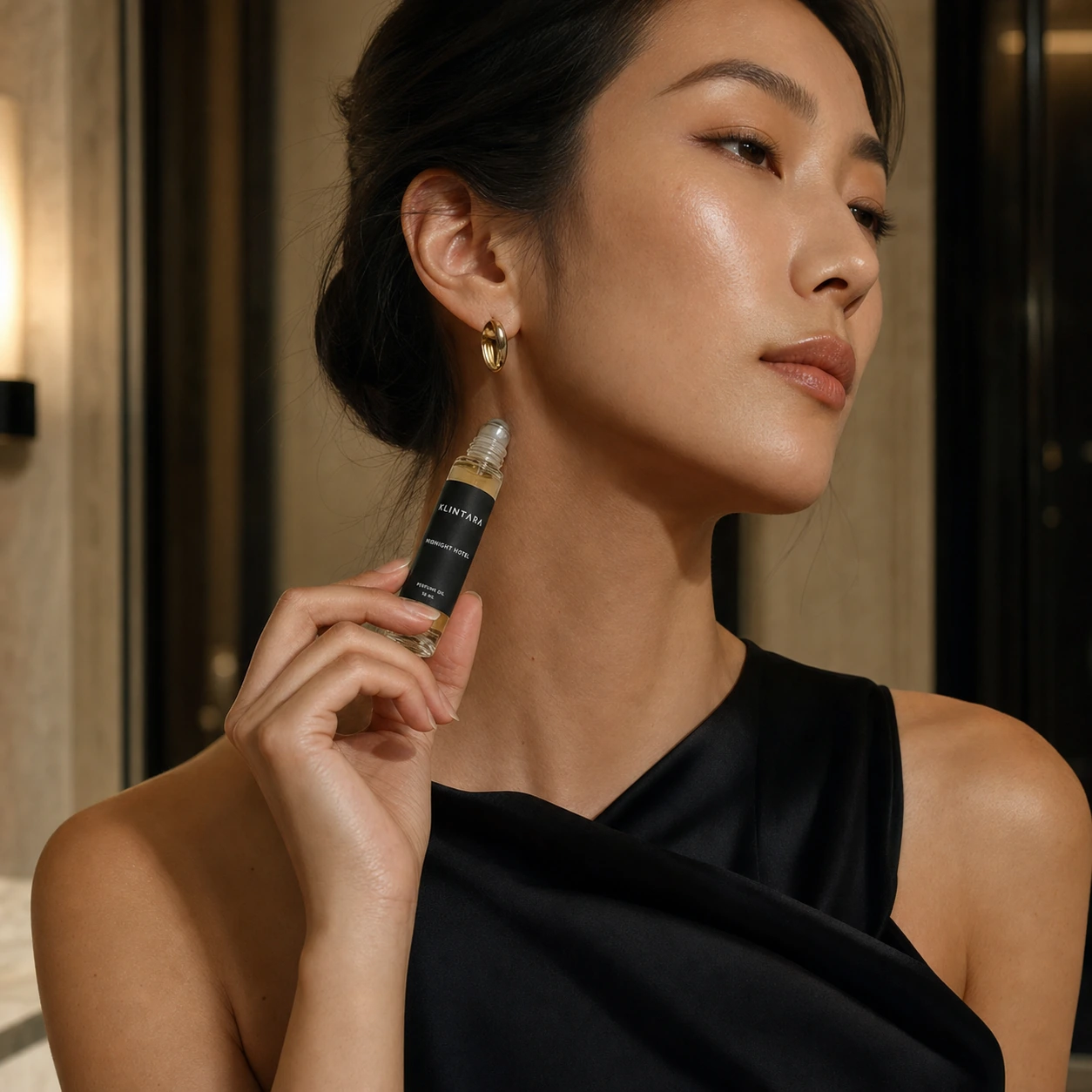 Adult East Asian woman applying Klintara perfume oil near her neck